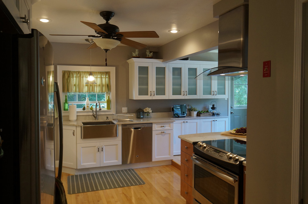 Example of a large transitional l-shaped light wood floor eat-in kitchen design in Boston with a farmhouse sink, shaker cabinets, white cabinets, quartz countertops, white backsplash, stone slab backsplash, stainless steel appliances and an island