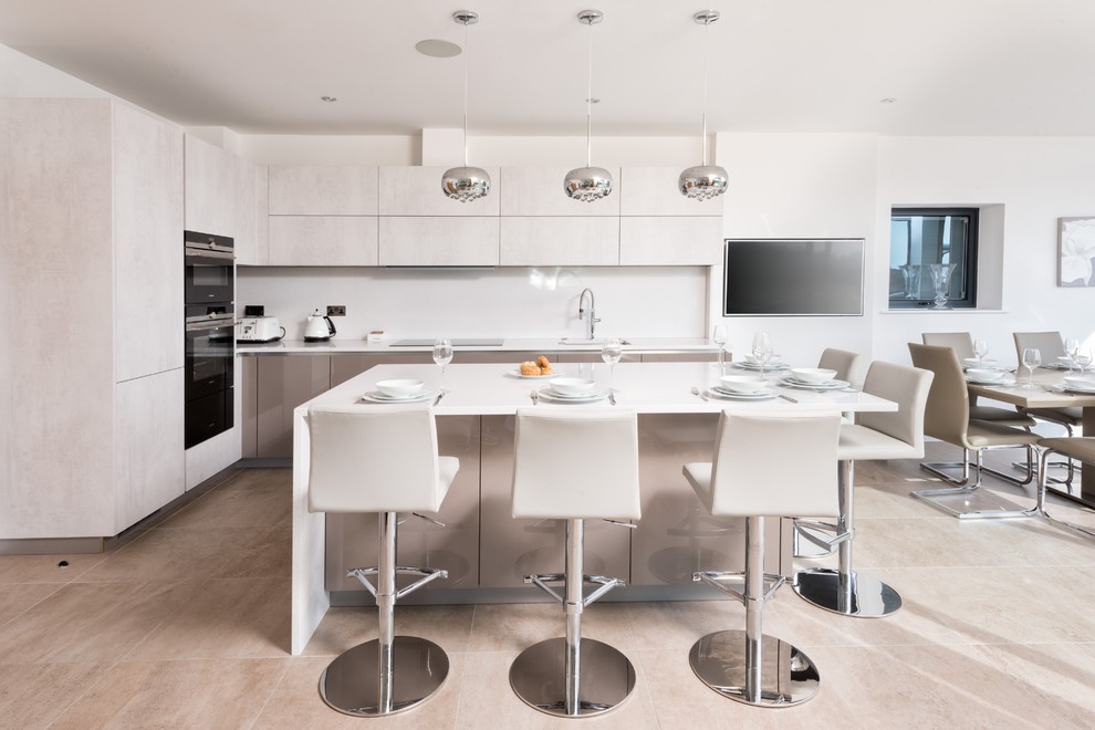 Photo of a mid-sized modern l-shaped kitchen in Berkshire with an undermount sink, flat-panel cabinets, beige cabinets, stainless steel appliances, with island, beige floor and beige benchtop.