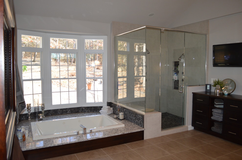 Example of a large transitional master gray tile and stone tile porcelain tile and beige floor drop-in bathtub design with flat-panel cabinets, dark wood cabinets, gray walls, a vessel sink, granite countertops and a hinged shower door