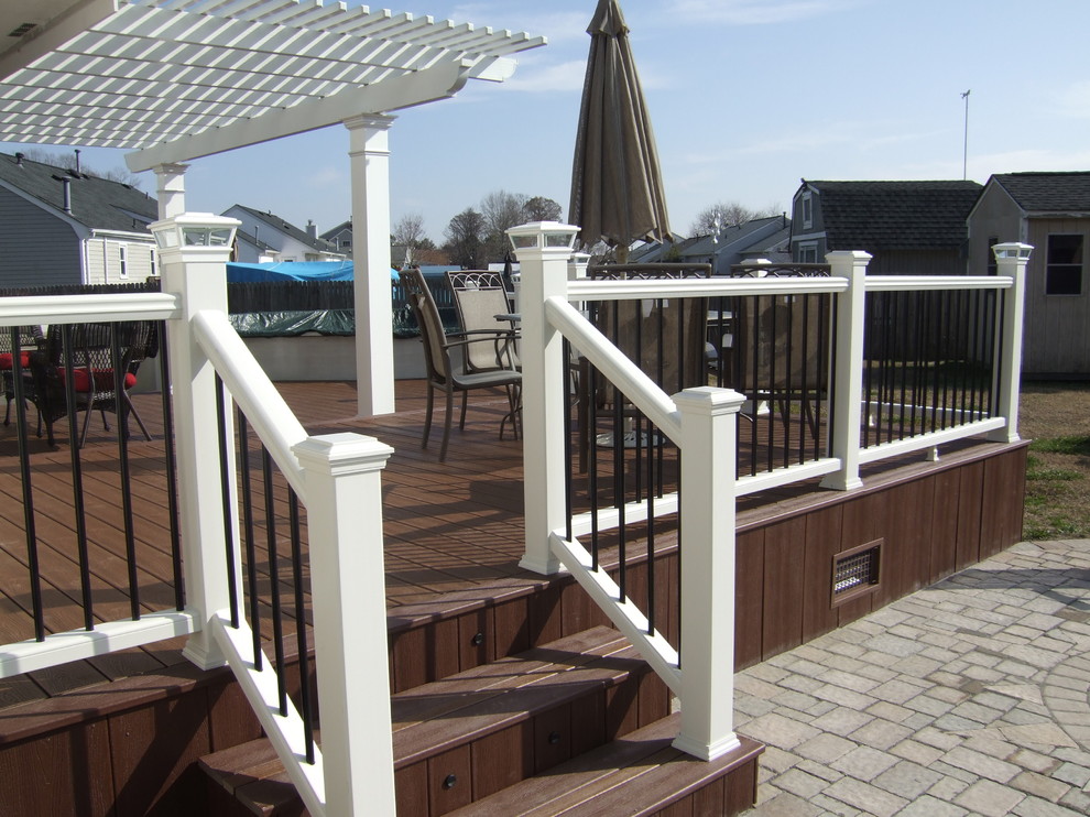 Photo of a large traditional backyard deck in Other with a pergola.