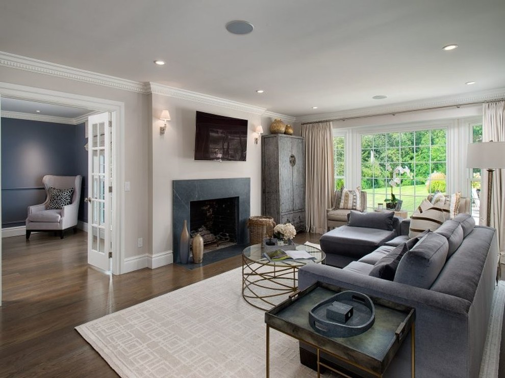 This is an example of a mid-sized transitional open concept family room in New York with beige walls, medium hardwood floors, a standard fireplace, a stone fireplace surround and a wall-mounted tv.