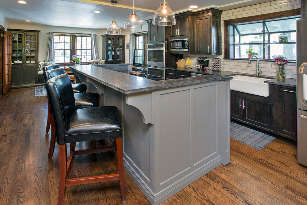 Example of a mid-sized transitional galley medium tone wood floor eat-in kitchen design with a farmhouse sink, beaded inset cabinets, dark wood cabinets, granite countertops, beige backsplash, ceramic backsplash, stainless steel appliances, multicolored walls and an island