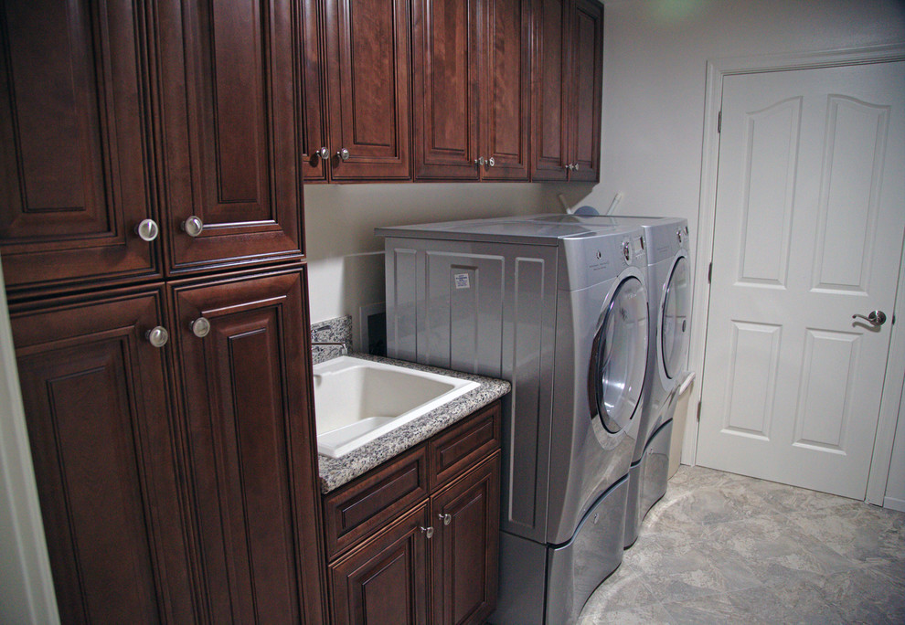 Inspiration for a traditional laundry room in Los Angeles with a drop-in sink, raised-panel cabinets, dark wood cabinets, granite benchtops, white walls and a side-by-side washer and dryer.