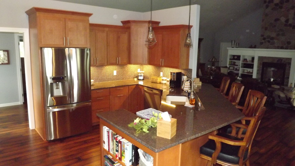 Open concept kitchen - transitional u-shaped medium tone wood floor open concept kitchen idea with an undermount sink, flat-panel cabinets, medium tone wood cabinets, granite countertops, black backsplash, glass tile backsplash, stainless steel appliances and a peninsula