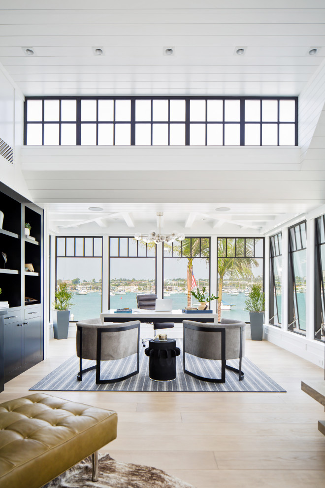 Inspiration for an expansive beach style study room in Orange County with white walls, light hardwood floors, a freestanding desk and beige floor.