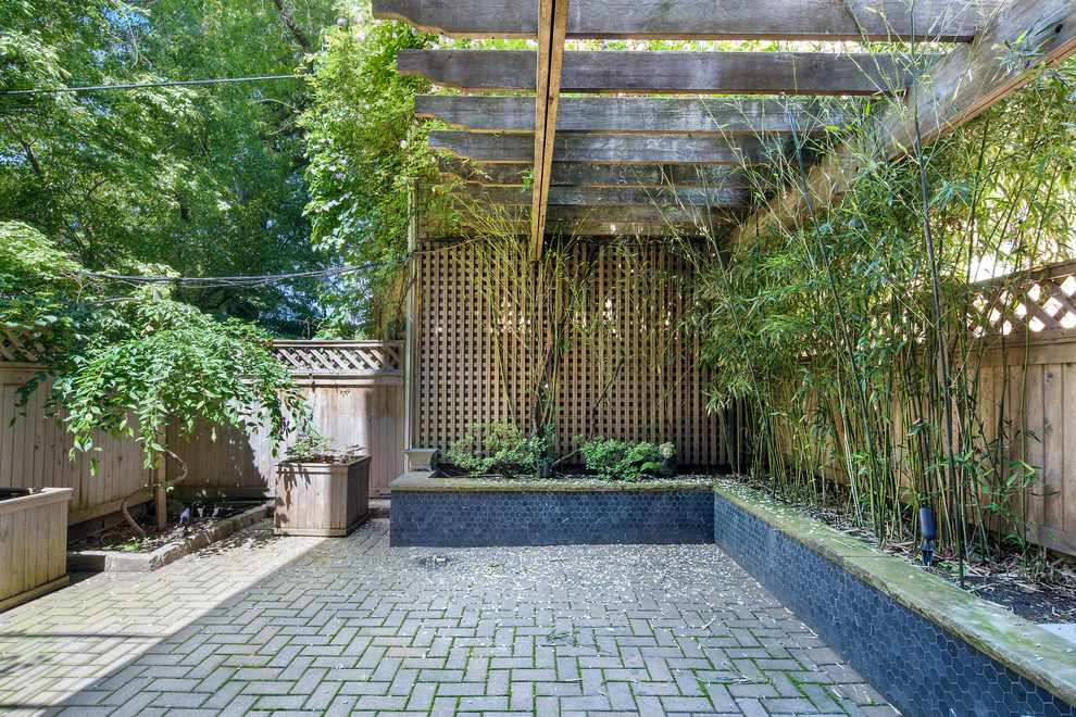 This is an example of a large traditional backyard patio in New York with a container garden, brick pavers and a pergola.