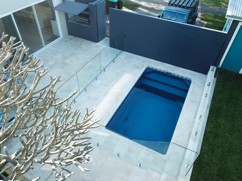 Exemple d'un piscine avec aménagement paysager arrière de taille moyenne et rectangle avec des pavés en pierre naturelle.