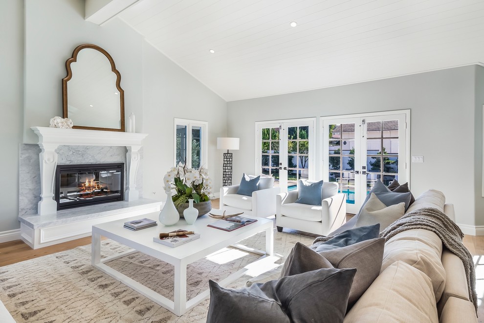 Inspiration for a large transitional open concept family room in Los Angeles with grey walls, medium hardwood floors, a standard fireplace and a wood fireplace surround.