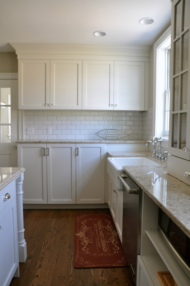 This is an example of a mid-sized traditional u-shaped kitchen in Grand Rapids with a farmhouse sink, flat-panel cabinets, white cabinets, quartz benchtops, stainless steel appliances, medium hardwood floors and with island.