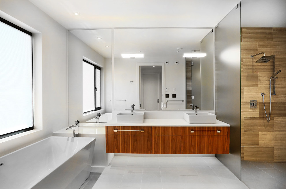 Expansive contemporary master bathroom in Vancouver with flat-panel cabinets, medium wood cabinets, a freestanding tub, a curbless shower, white tile, stone tile, white walls, cement tiles, a vessel sink, engineered quartz benchtops, grey floor and an open shower.