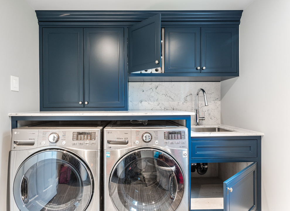 Inspiration for a small traditional single-wall dedicated laundry room in Montreal with an undermount sink, blue cabinets, quartz benchtops, white walls, ceramic floors, a side-by-side washer and dryer, grey floor, grey benchtop and recessed-panel cabinets.