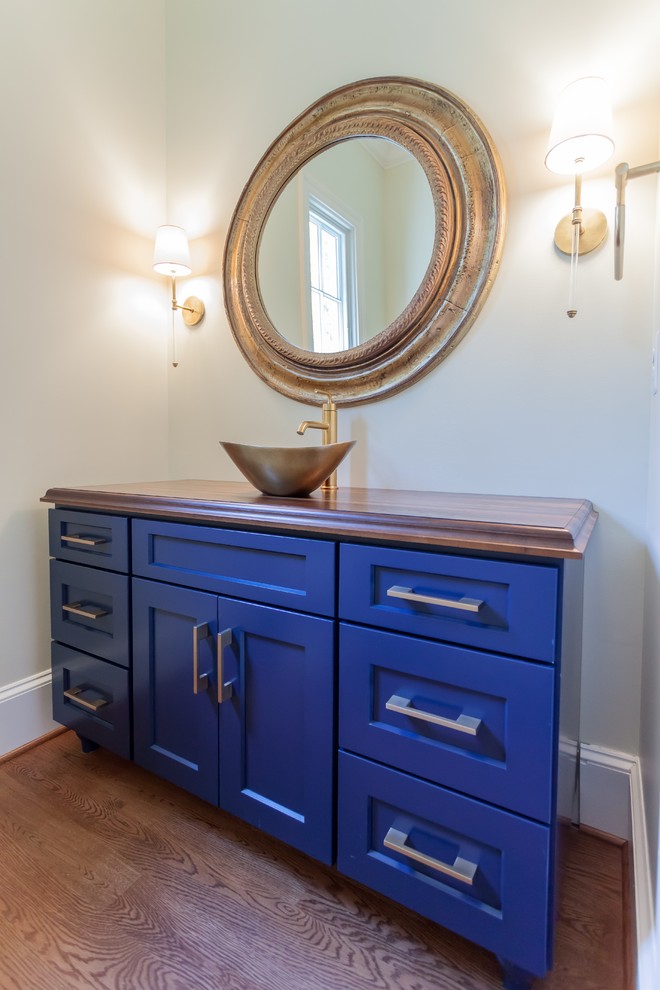 Photo of a traditional powder room in DC Metro with furniture-like cabinets, blue cabinets, yellow walls, medium hardwood floors, a vessel sink, wood benchtops, brown floor and brown benchtops.