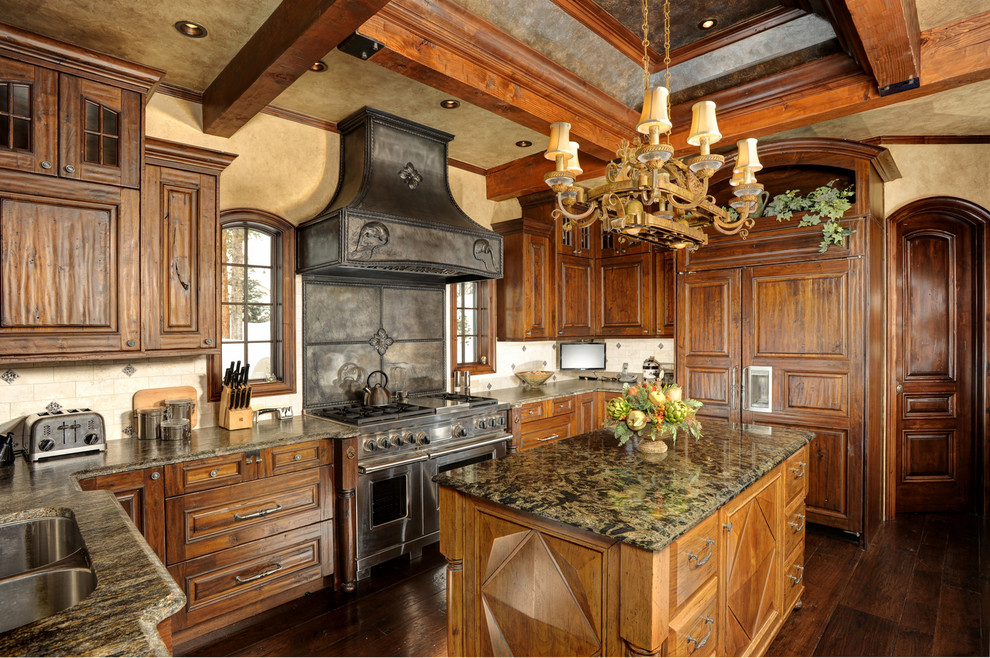 Photo of a country u-shaped kitchen in Denver with a double-bowl sink, raised-panel cabinets, medium wood cabinets, beige splashback, panelled appliances, dark hardwood floors and with island.