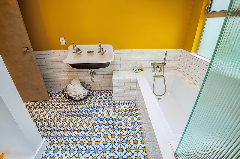 Mid-sized midcentury 3/4 bathroom in Los Angeles with open cabinets, an undermount tub, a corner shower, a two-piece toilet, white tile, stone tile, yellow walls, cement tiles, a trough sink, solid surface benchtops, blue floor and a hinged shower door.