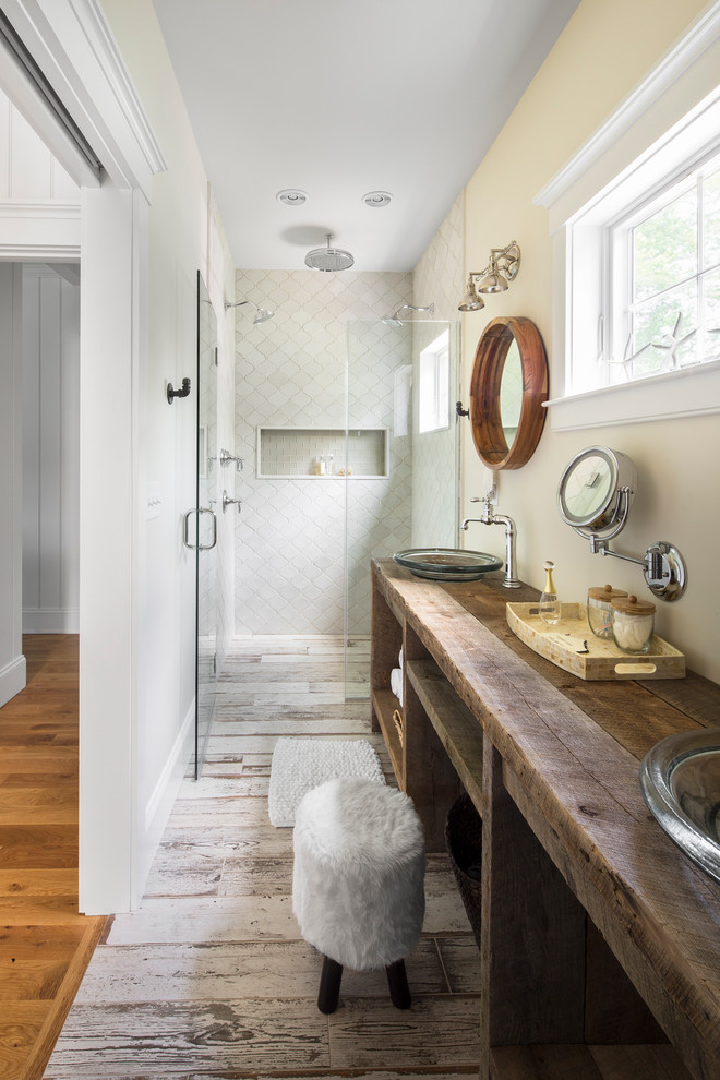 This is an example of a mid-sized beach style 3/4 bathroom in Boston with open cabinets, dark wood cabinets, a vessel sink, wood benchtops, a curbless shower, yellow walls, a one-piece toilet, white tile, ceramic tile, ceramic floors, a hinged shower door and brown benchtops.