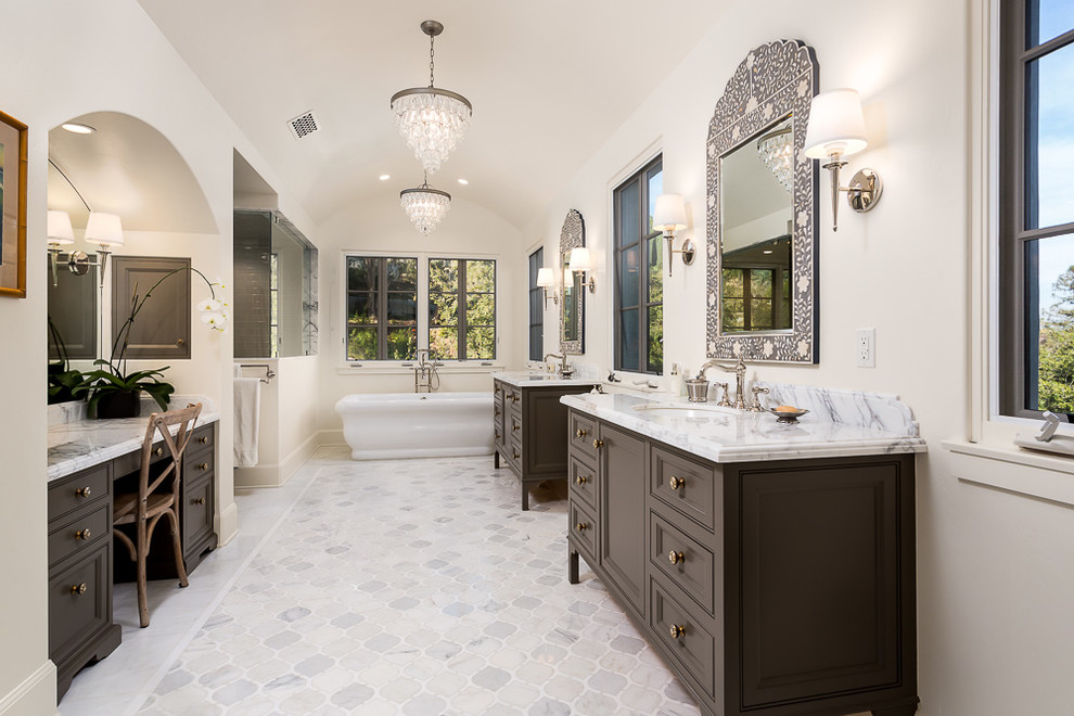 Inspiration for a traditional master bathroom in Los Angeles with recessed-panel cabinets, brown cabinets, a freestanding tub, white walls, marble benchtops, a corner shower, a one-piece toilet, an undermount sink and a hinged shower door.