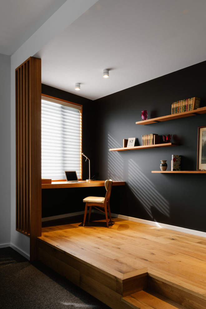 Mid-sized contemporary study room in Adelaide with black walls, a built-in desk, brown floor and light hardwood floors.