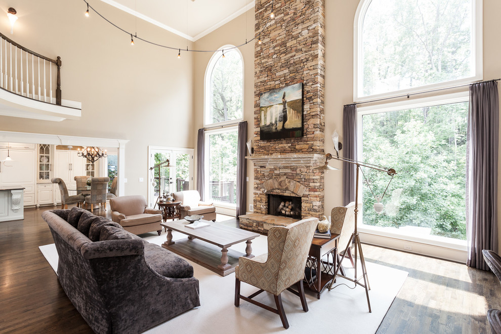 This is an example of a large transitional formal open concept living room in Atlanta with beige walls, dark hardwood floors, a standard fireplace, a stone fireplace surround, no tv and brown floor.
