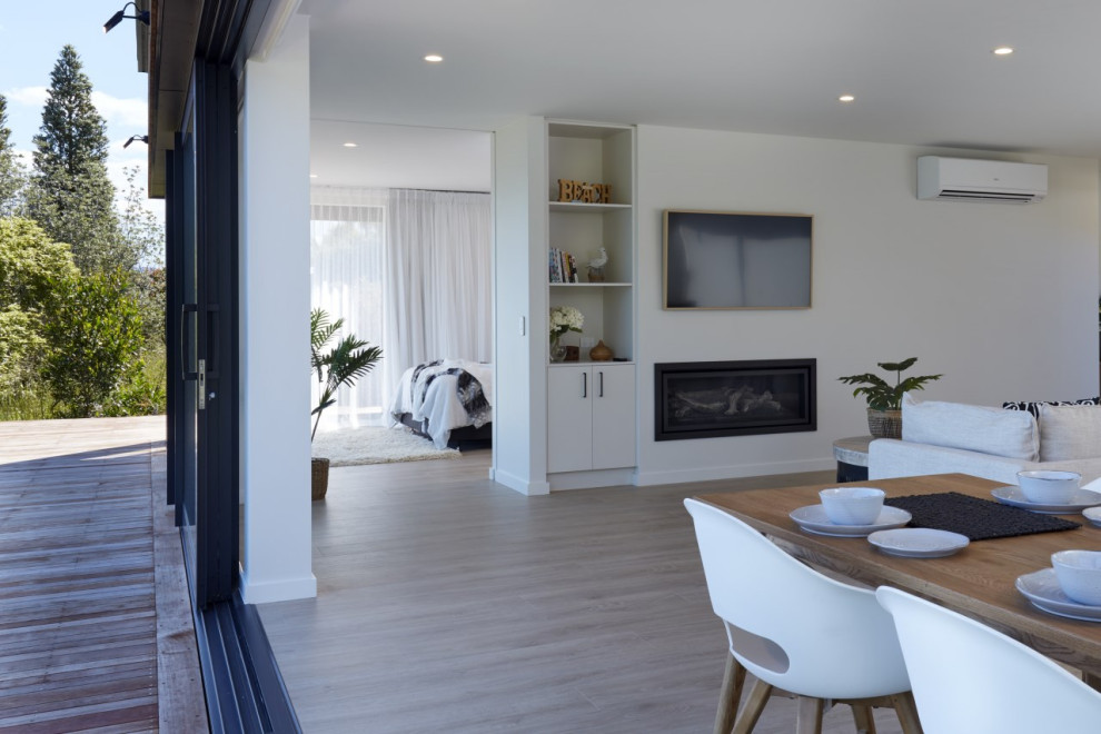 Esempio di un soggiorno stile marinaro di medie dimensioni e aperto con pavimento in laminato, camino classico e TV a parete