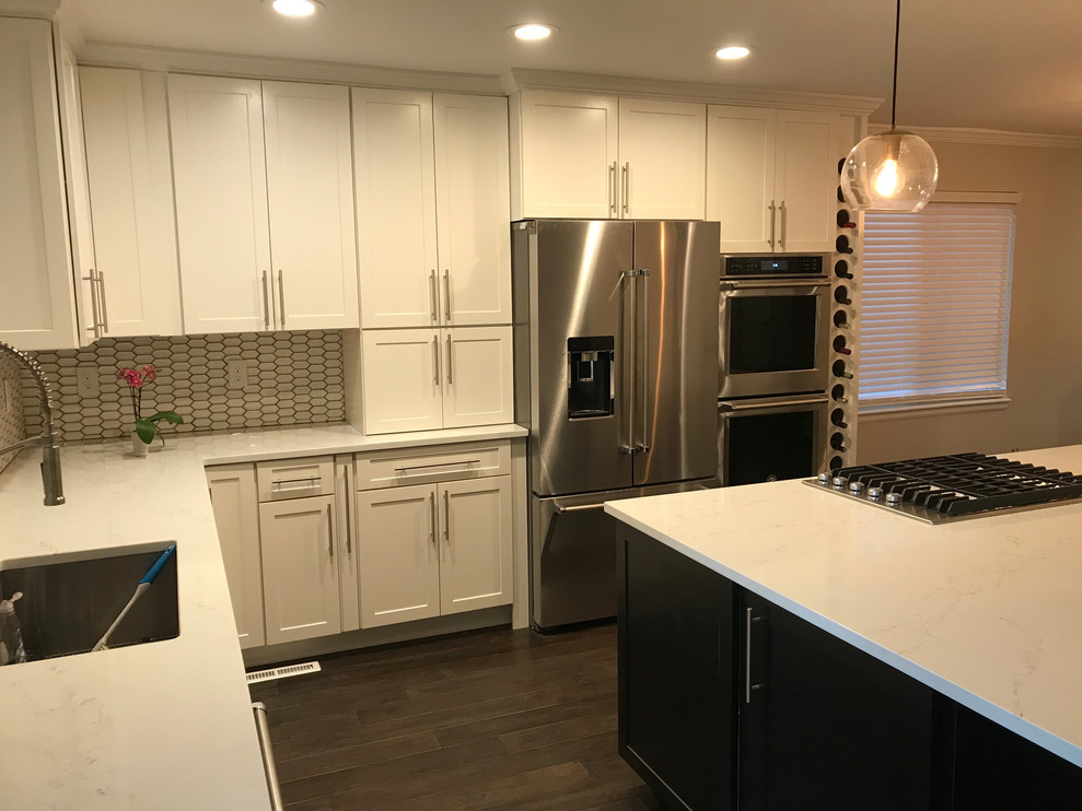 Small transitional l-shaped dark wood floor and brown floor open concept kitchen photo in Birmingham with shaker cabinets, white cabinets, white backsplash, stainless steel appliances, an island and white countertops
