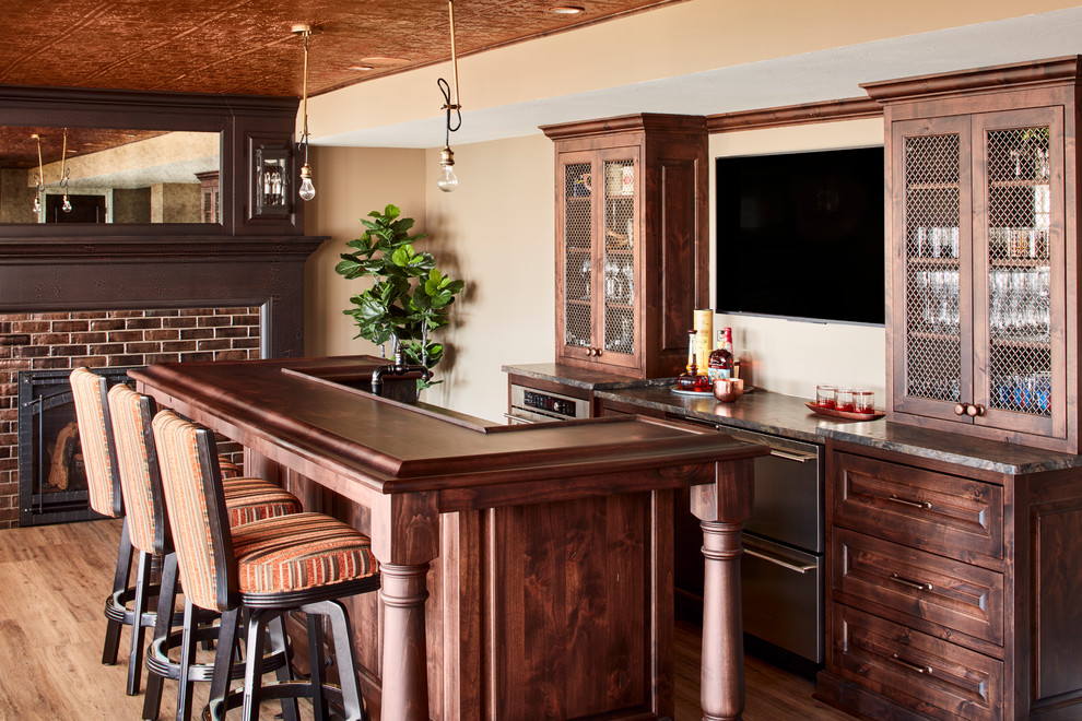 Photo of a beach style seated home bar in Milwaukee with dark wood cabinets, medium hardwood floors and brown benchtop.