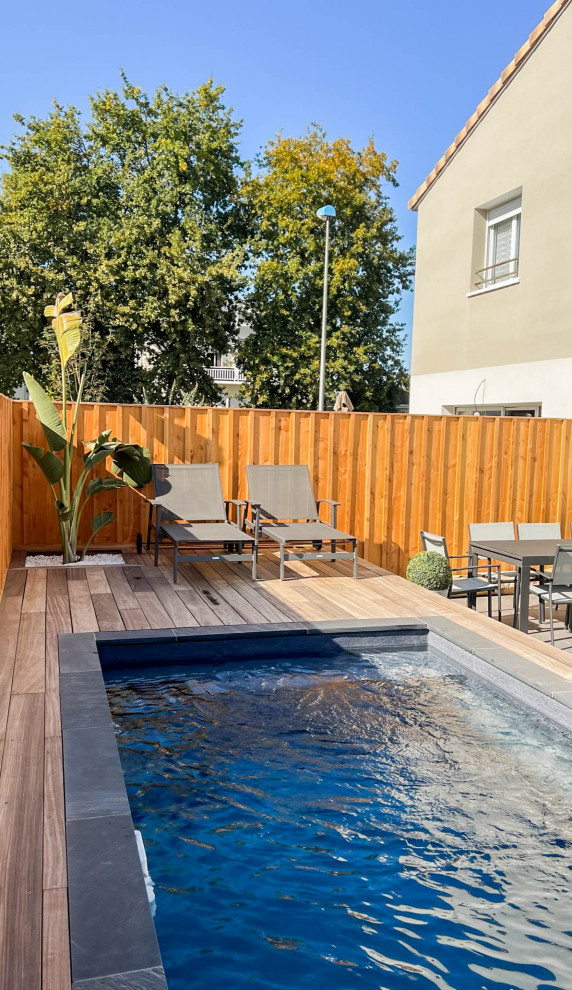 Cette photo montre un petit piscine avec aménagement paysager arrière moderne rectangle avec une terrasse en bois.