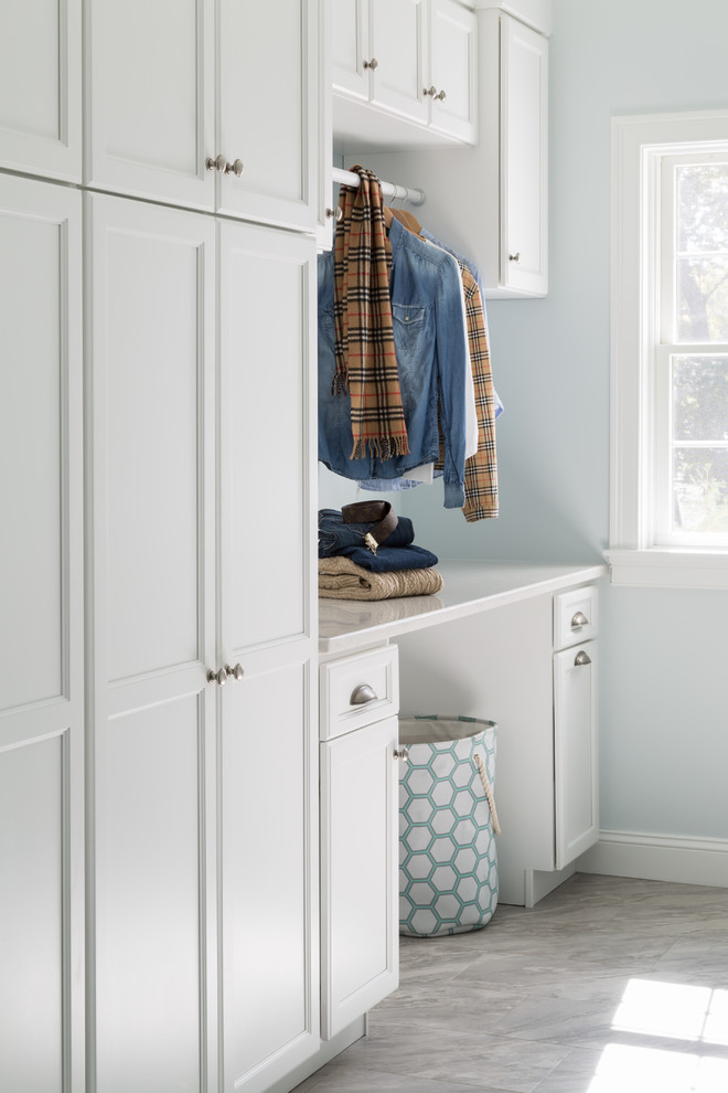 Design ideas for a transitional galley dedicated laundry room in Providence with recessed-panel cabinets, white cabinets, quartz benchtops, blue walls and porcelain floors.