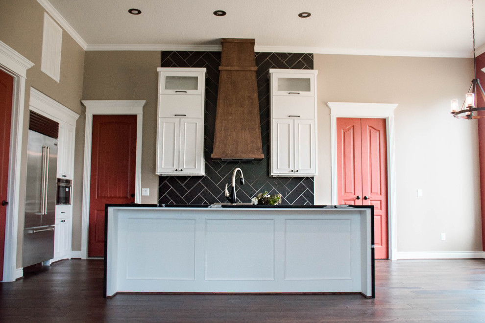 Inredning av ett modernt mellanstort svart linjärt svart kök och matrum, med en enkel diskho, luckor med infälld panel, vita skåp, bänkskiva i kvarts, svart stänkskydd, stänkskydd i cementkakel, rostfria vitvaror, mellanmörkt trägolv, en köksö och brunt golv