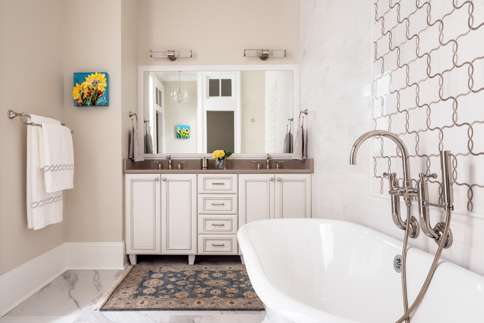 Large traditional master bathroom in New Orleans with raised-panel cabinets, beige cabinets, a freestanding tub, an alcove shower, a two-piece toilet, white tile, marble, beige walls, marble floors, an undermount sink, quartzite benchtops, white floor, a hinged shower door and brown benchtops.