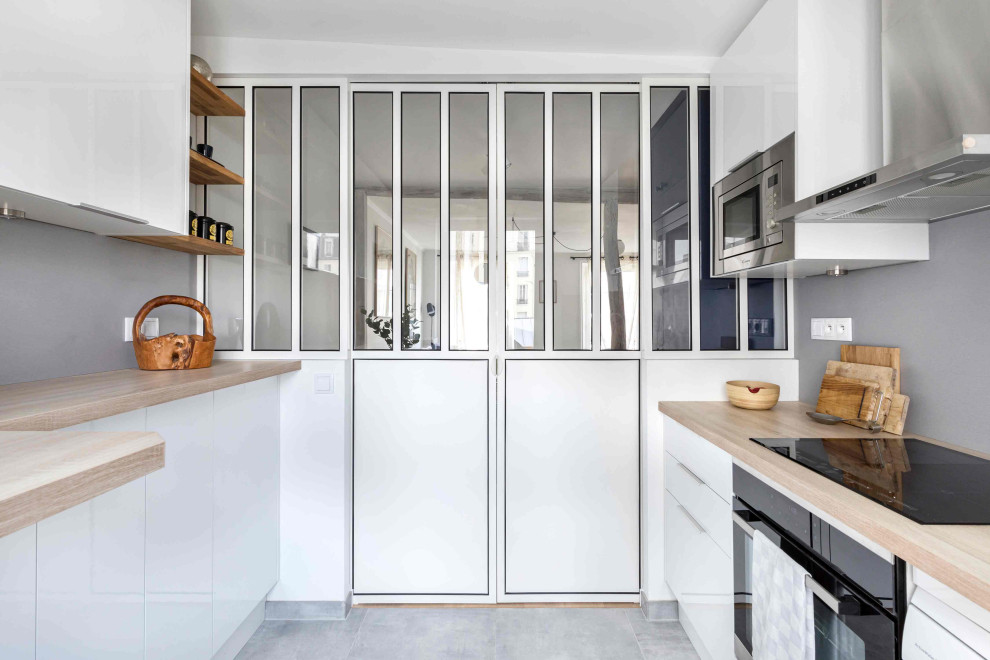 Photo of a small traditional u-shaped open plan kitchen in Paris with an undermount sink, white cabinets, laminate benchtops, grey splashback, stainless steel appliances, grey floor and beige benchtop.