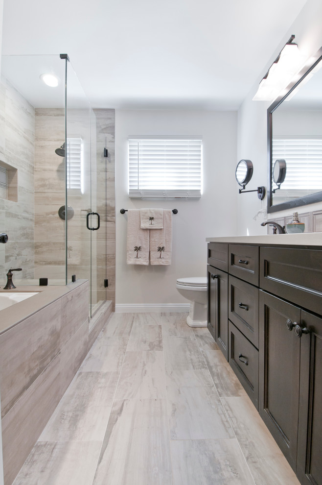 Design ideas for a large transitional master bathroom in Los Angeles with recessed-panel cabinets, dark wood cabinets, an alcove tub, a corner shower, a two-piece toilet, beige tile, porcelain tile, grey walls, porcelain floors, an undermount sink, beige floor and a hinged shower door.