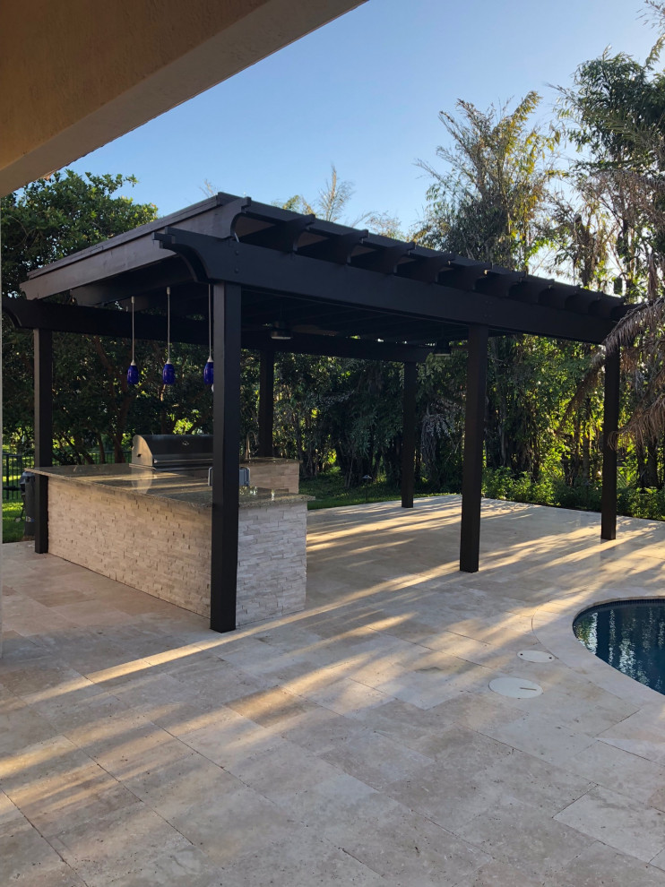 Inspiration for an expansive modern backyard patio in Miami with an outdoor kitchen, natural stone pavers and a pergola.