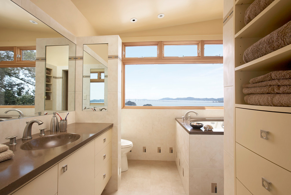 Contemporary bathroom in San Francisco with an integrated sink, flat-panel cabinets, beige cabinets, beige tile, a japanese tub and brown benchtops.