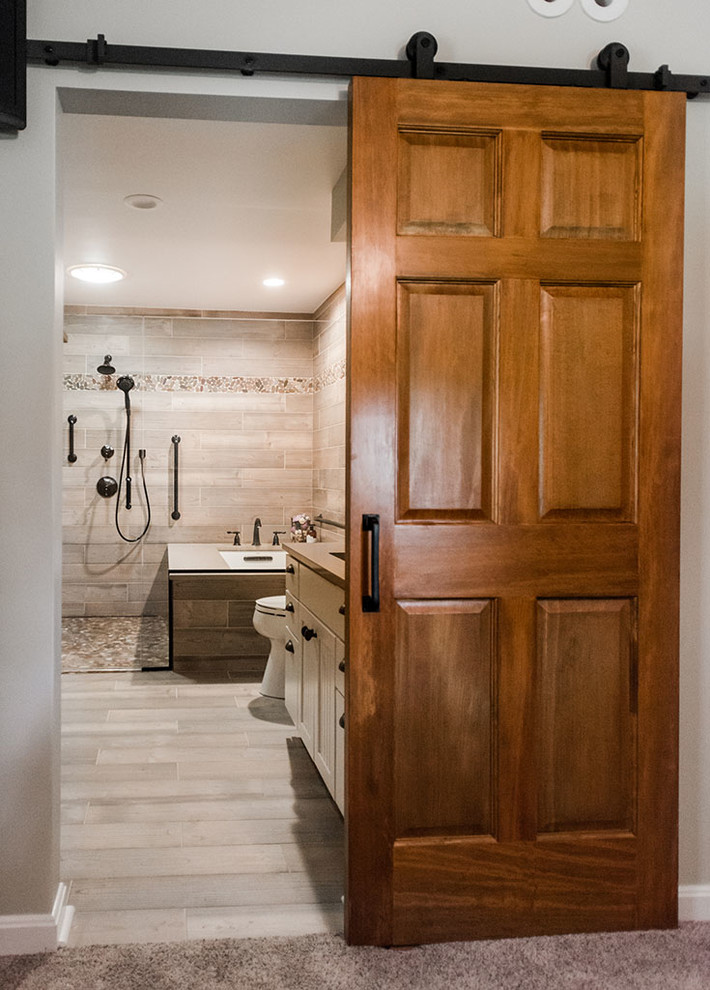 This is an example of a mid-sized contemporary master bathroom in Baltimore with light wood cabinets, a corner tub, a shower/bathtub combo, a one-piece toilet, multi-coloured tile, porcelain tile, beige walls, porcelain floors, a drop-in sink, engineered quartz benchtops, multi-coloured floor and a hinged shower door.