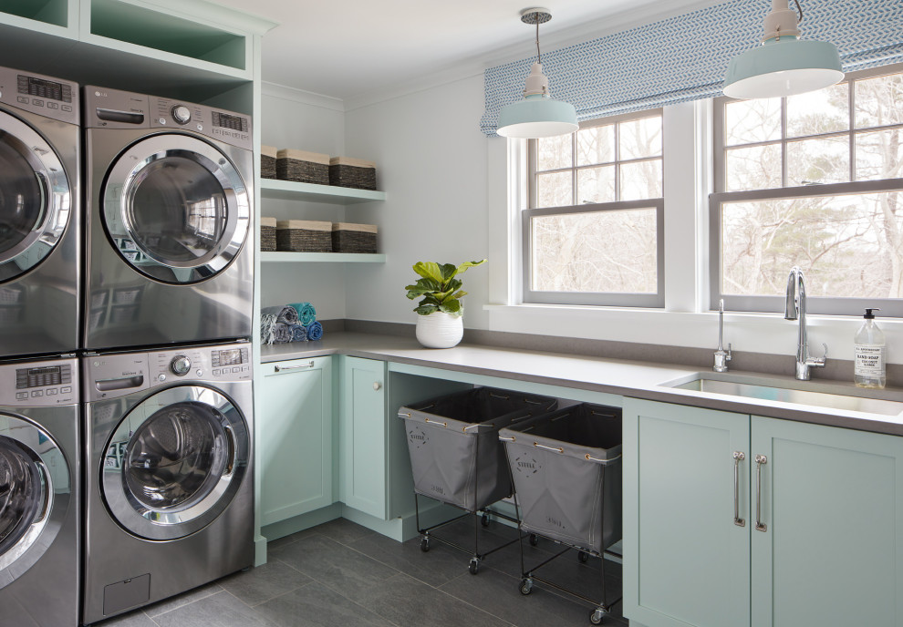 Bild på en stor vintage grå u-formad grått tvättstuga enbart för tvätt, med en undermonterad diskho, turkosa skåp, bänkskiva i kvarts, vita väggar, klinkergolv i keramik, en tvättpelare och grått golv