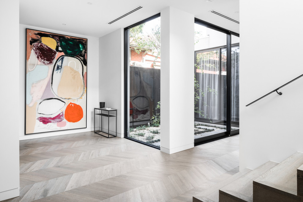 Inspiration for a mid-sized modern light wood floor and gray floor hallway remodel in Melbourne with white walls