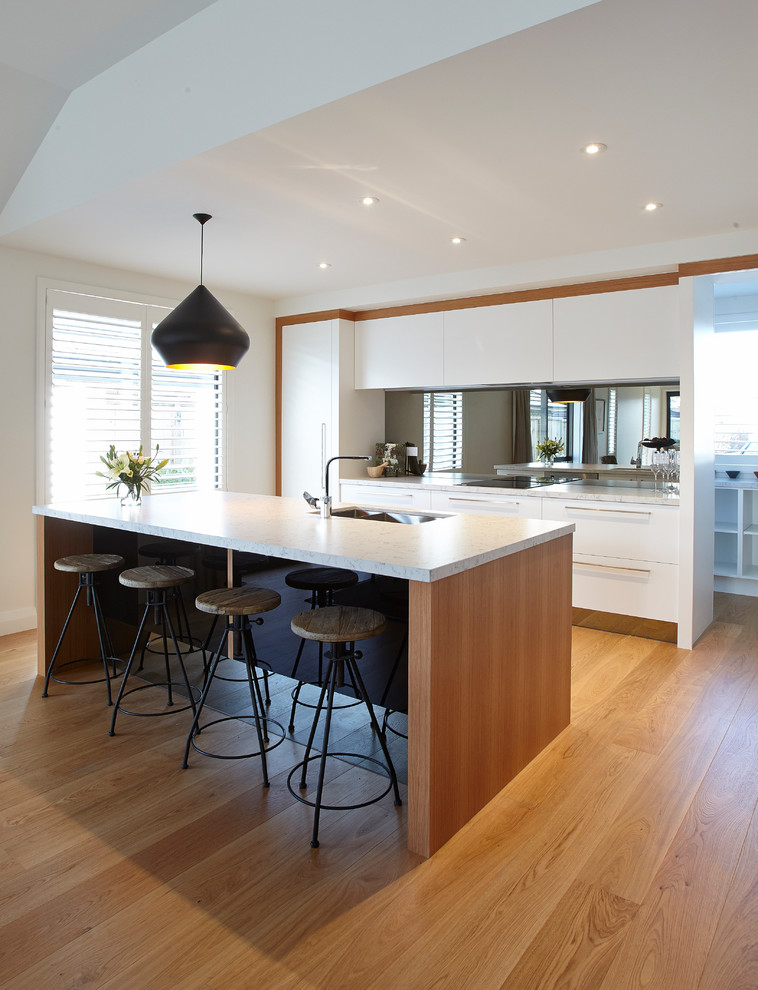 Design ideas for a contemporary kitchen in Hamilton with an undermount sink, marble benchtops, mirror splashback, panelled appliances, medium hardwood floors, with island, flat-panel cabinets and white cabinets.