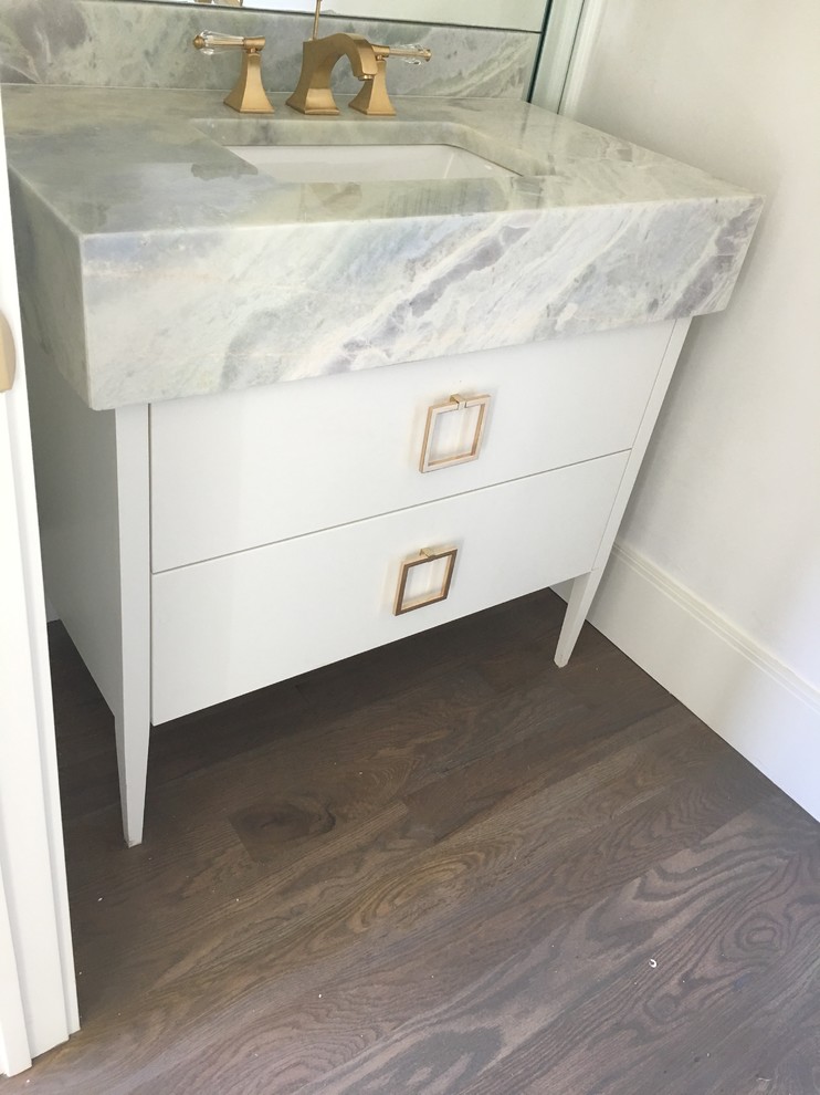 Design ideas for a mid-sized modern powder room in Dallas with recessed-panel cabinets, white cabinets, a two-piece toilet, white walls, cement tiles, an undermount sink, marble benchtops, grey floor and white benchtops.