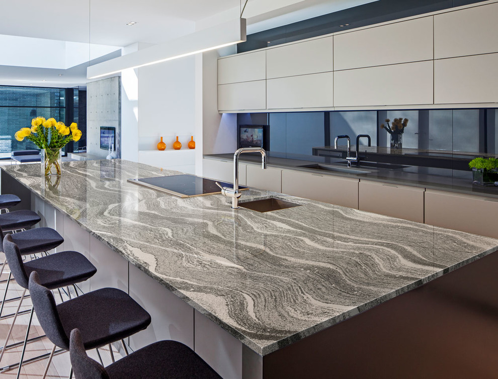 Photo of a large contemporary galley eat-in kitchen in Other with an undermount sink, flat-panel cabinets, beige cabinets, quartz benchtops, black splashback, stone slab splashback, stainless steel appliances and with island.