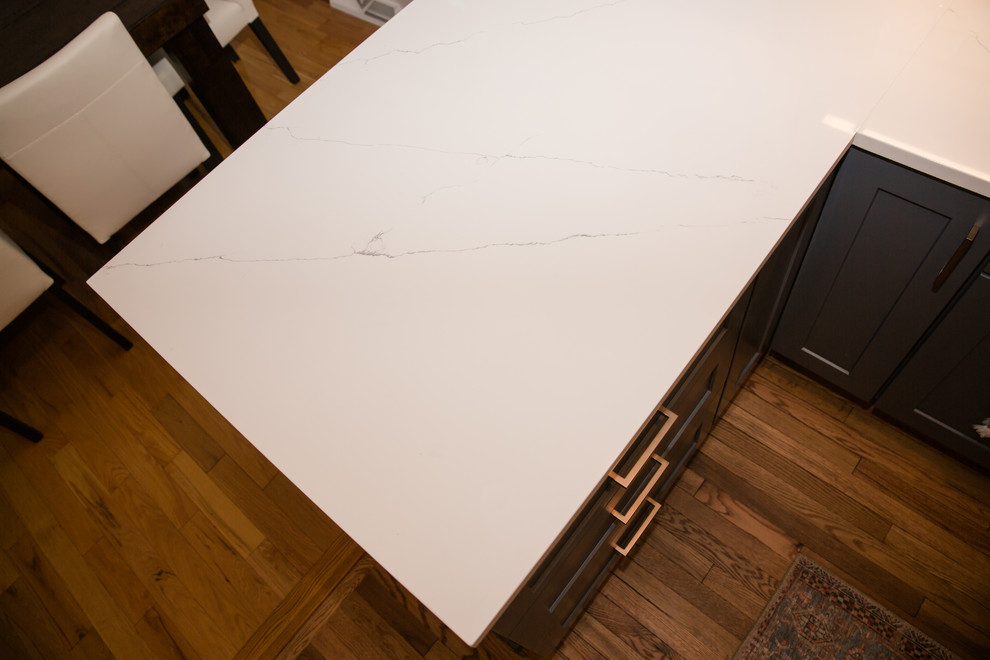 Mid-sized transitional galley medium tone wood floor and brown floor eat-in kitchen photo with an undermount sink, shaker cabinets, blue cabinets, solid surface countertops, white backsplash, ceramic backsplash, stainless steel appliances, a peninsula and white countertops