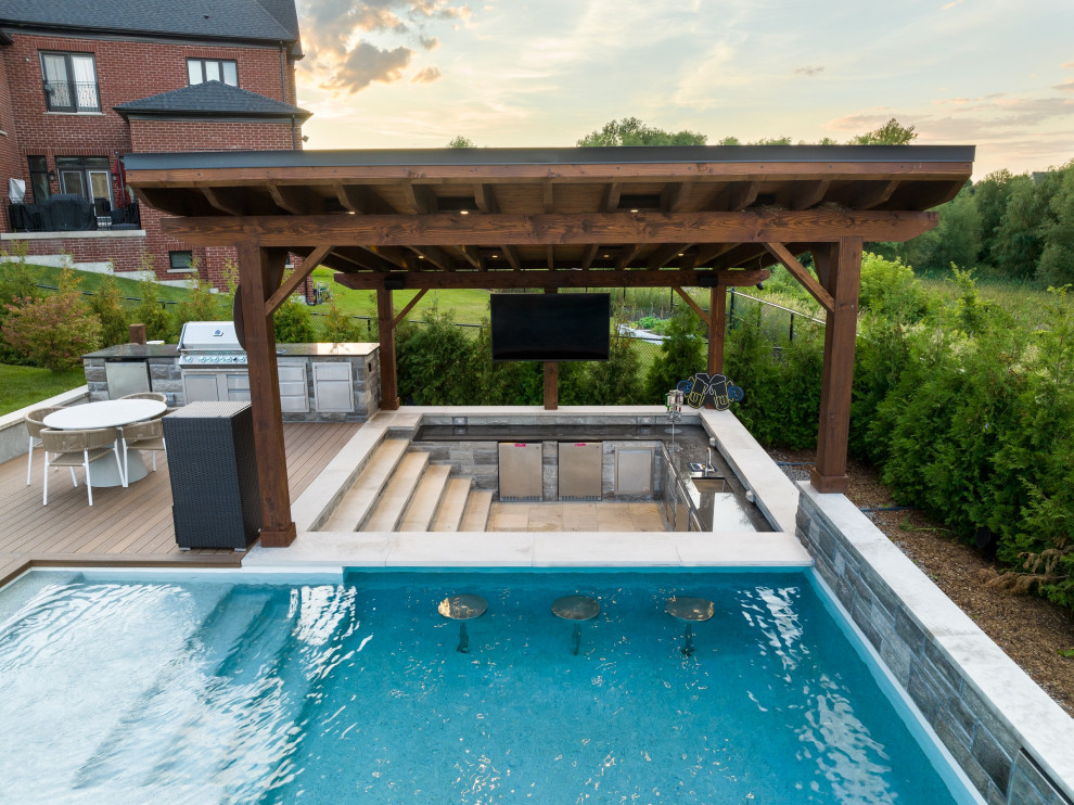 Modelo de casa de la piscina y piscina tradicional renovada de tamaño medio rectangular en patio trasero con entablado