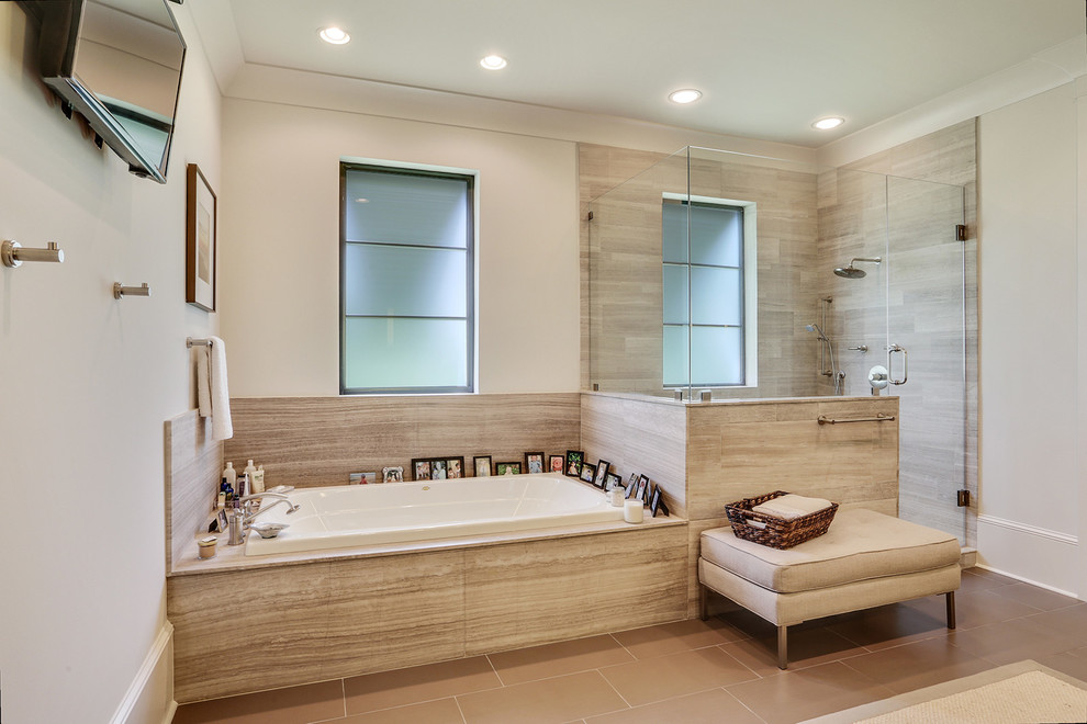 This is an example of a transitional bathroom in New Orleans with a drop-in tub, a corner shower, beige walls and a hinged shower door.