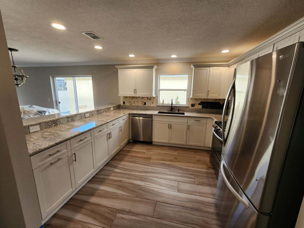 Kitchen - large galley kitchen idea with shaker cabinets, white cabinets, quartz countertops, an island and white countertops