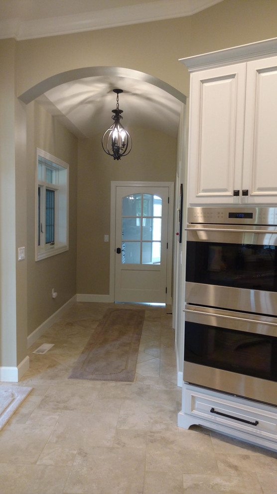 Example of a large transitional ceramic tile and beige floor kitchen design in Chicago with raised-panel cabinets, white cabinets and stainless steel appliances