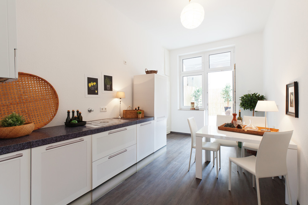 Photo of a large contemporary single-wall eat-in kitchen in Dortmund with shaker cabinets, white cabinets, dark hardwood floors, no island and panelled appliances.