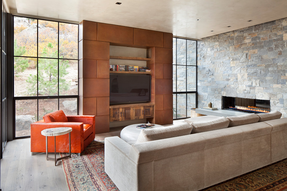 Expansive contemporary enclosed family room in Denver with a stone fireplace surround, a built-in media wall, grey floor, light hardwood floors and a ribbon fireplace.