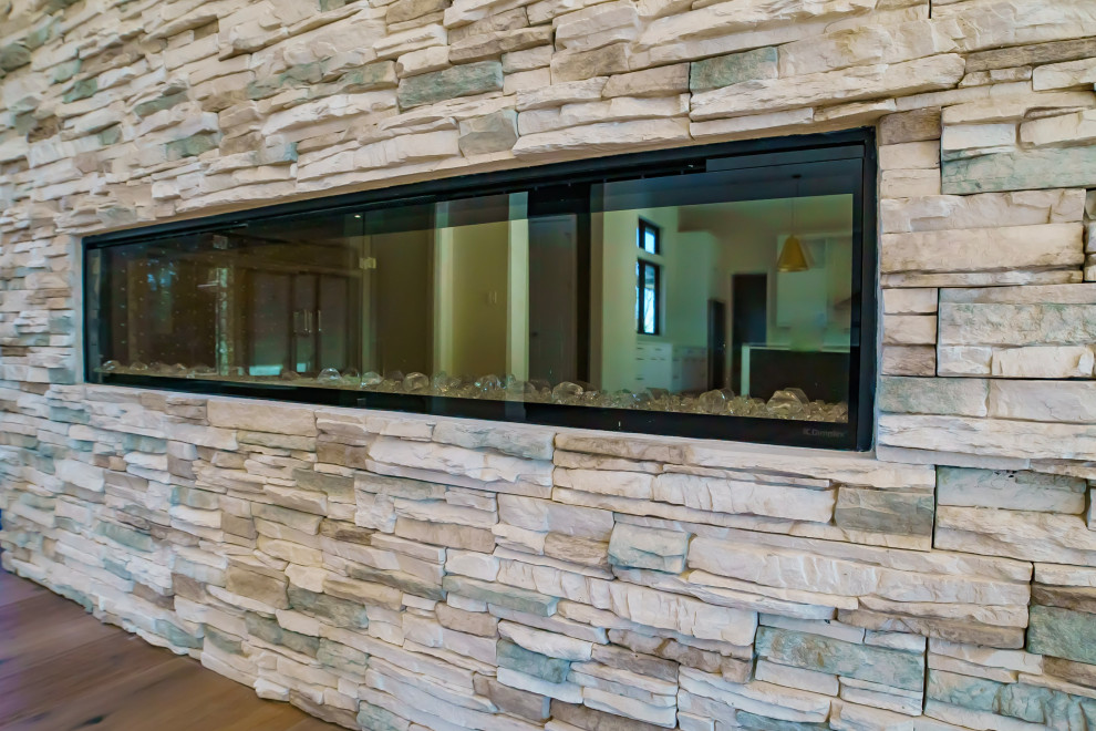 ソルトレイクシティにある高級な広いミッドセンチュリースタイルのおしゃれなオープンリビング (ベージュの壁、無垢フローリング、横長型暖炉、積石の暖炉まわり、茶色い床) の写真