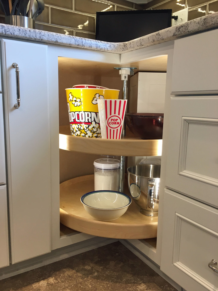 Example of a large transitional l-shaped vinyl floor and beige floor eat-in kitchen design with a double-bowl sink, recessed-panel cabinets, white cabinets, granite countertops, brown backsplash, ceramic backsplash, stainless steel appliances and an island