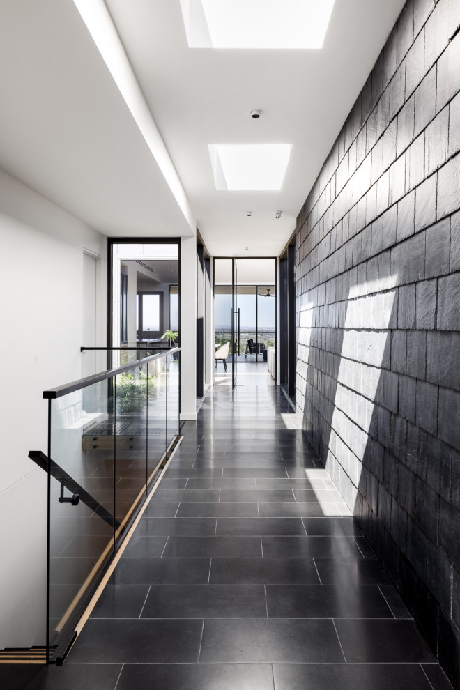 На фото: коридор среднего размера в современном стиле с черными стенами, панелями на части стены, черным полом и полом из керамогранита с