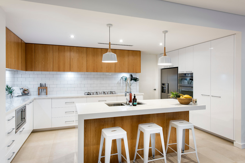 This is an example of a mid-sized beach style kitchen in Perth with an undermount sink, quartz benchtops, white splashback, subway tile splashback, stainless steel appliances, porcelain floors and with island.